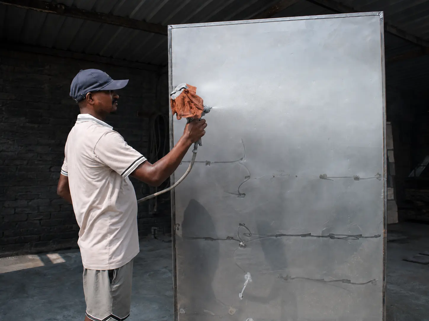 Craftsperson spray painting a steel almirah